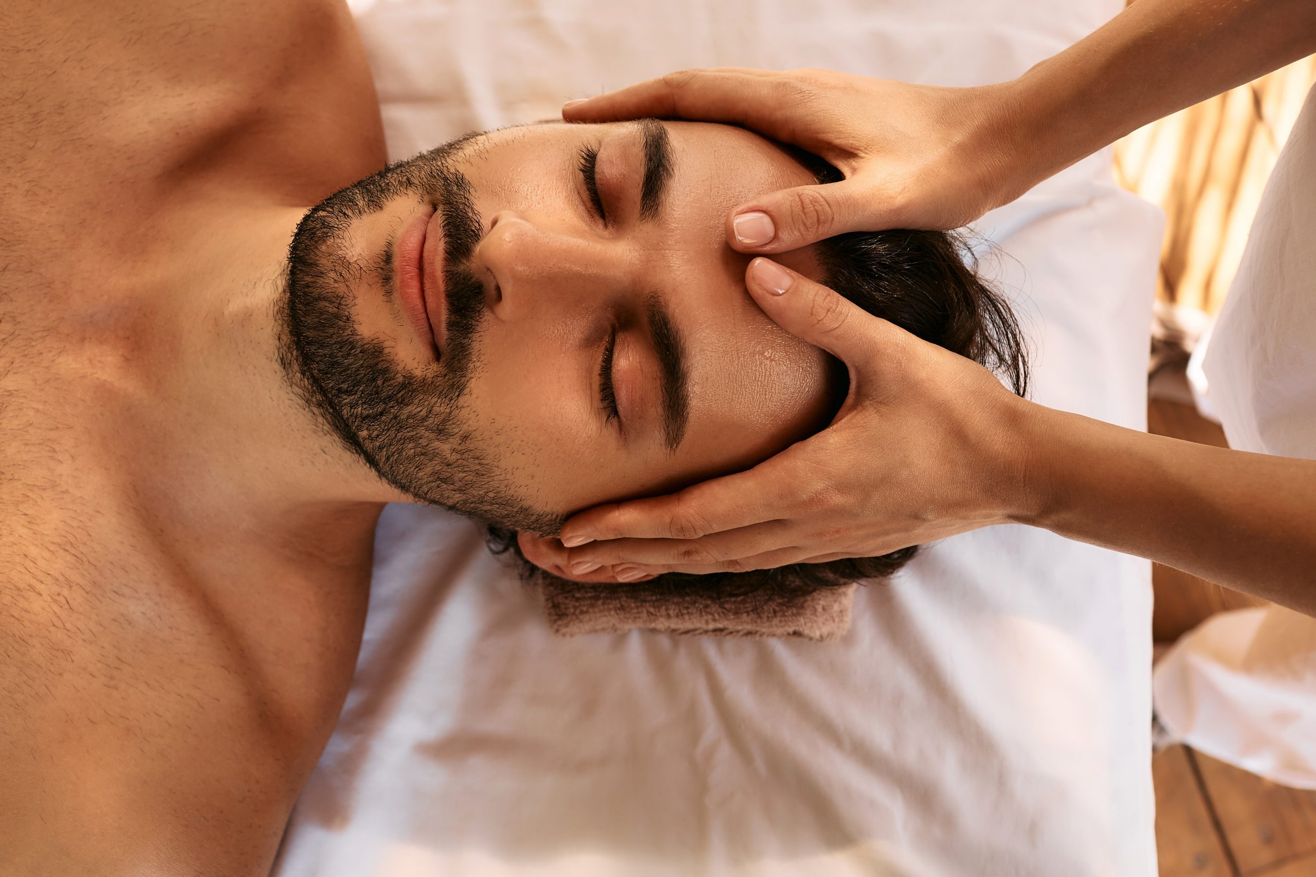 Relaxing anti-stress head massage. Handsome man relaxes in a massage parlor during head massage, top view